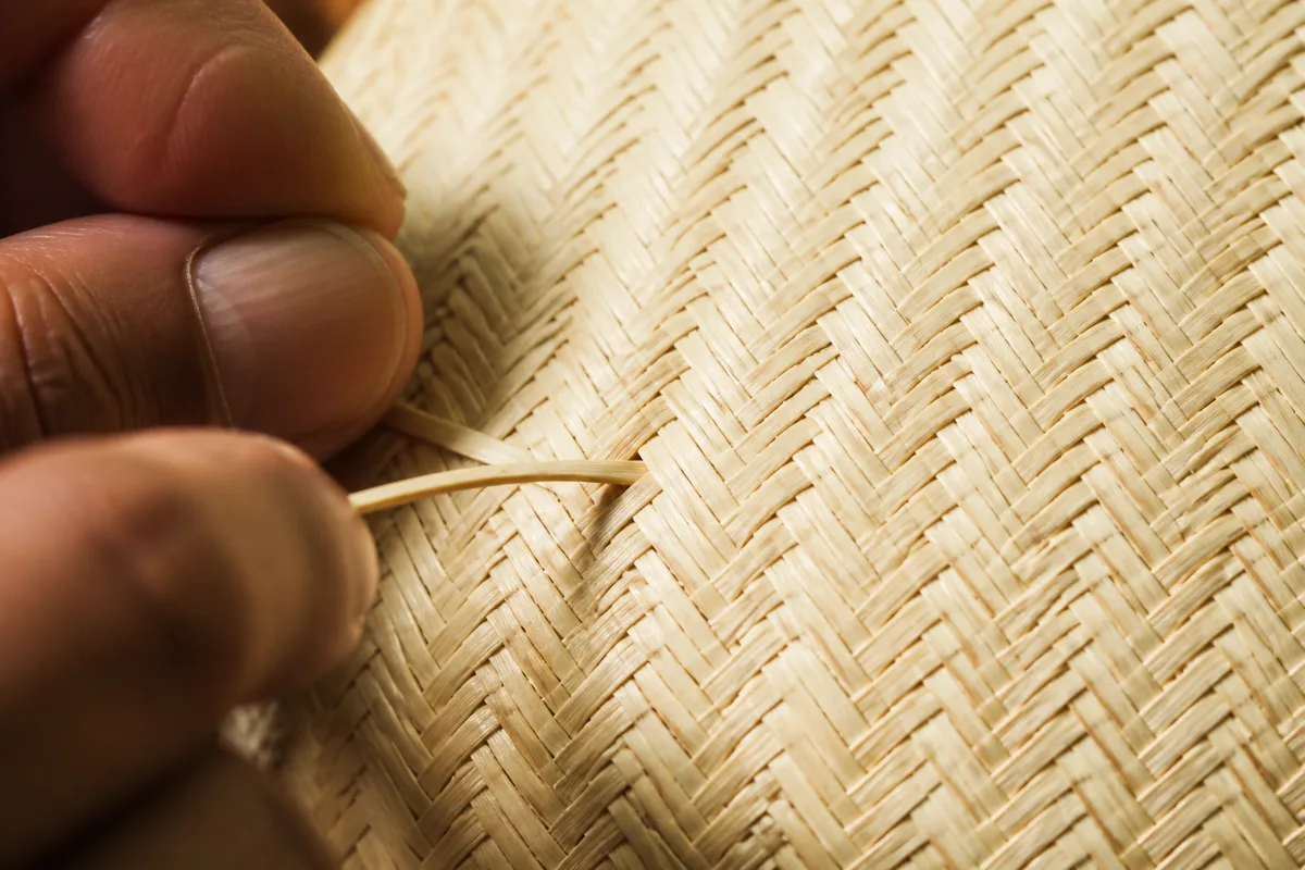 Gros plan sur le tressage serré en chevrons d’une paille claire, lumière rasante